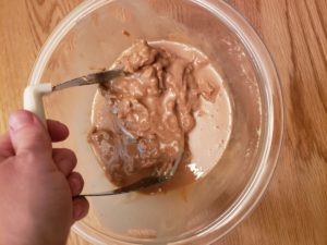 stirring peanut butter in glass bowl